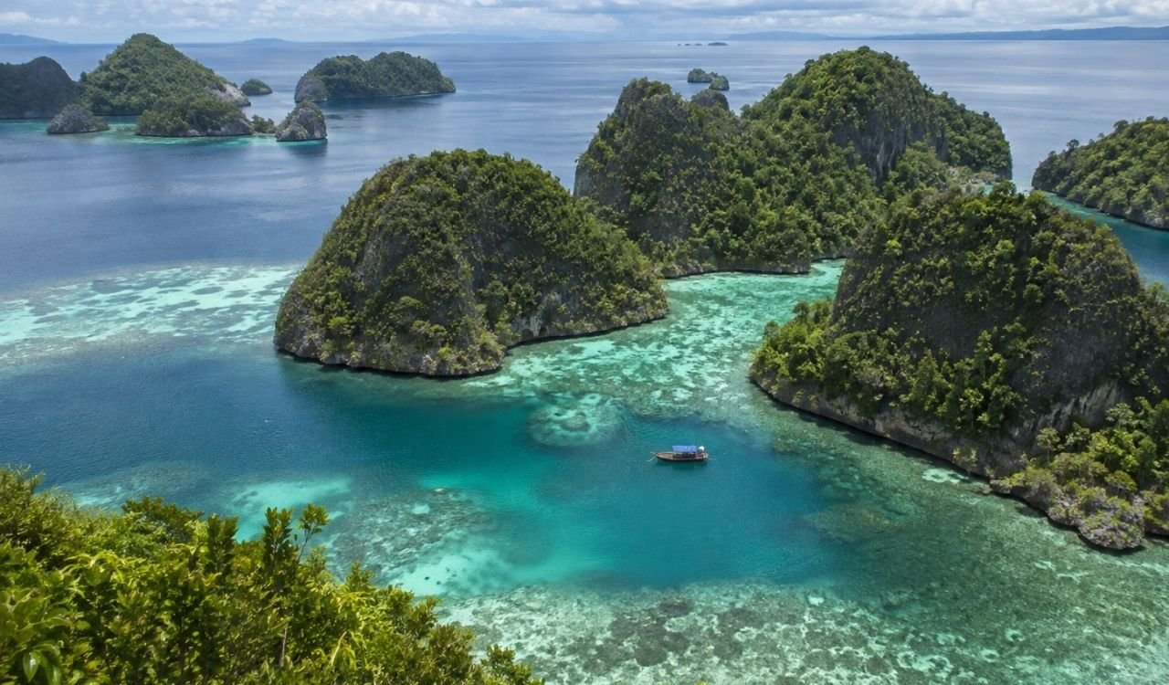 Turquoise lagoons surrounding forest-covered limestone islands in Raja Ampat, Indonesia
