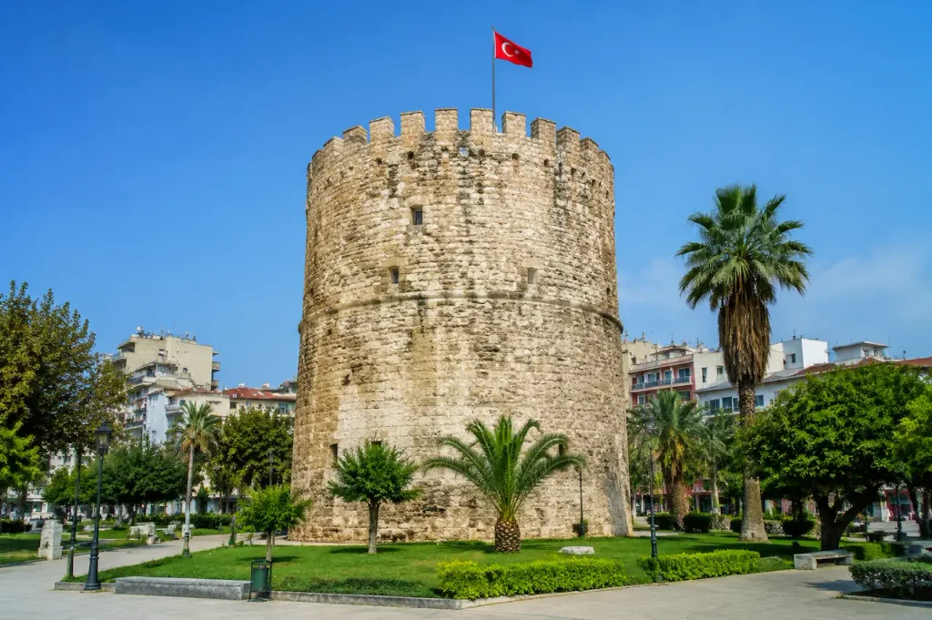 Hıdırlık Tower with a Turkish flag in a palm-lined park in Antalya, Turkey.