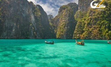 Scenic view of Phi Phi Islands limestone cliffs rising above crystal clear turquoise waters with boat in foreground