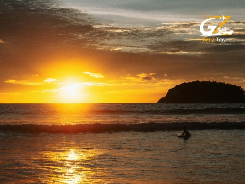 Stunning sunset over a tropical beach in Phuket with golden skies and calm turquoise water