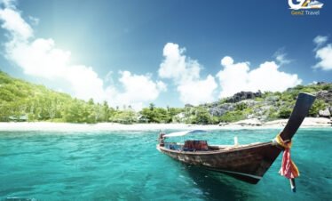 Traditional longtail boat sailing through crystal clear waters between tropical islands in Thailand