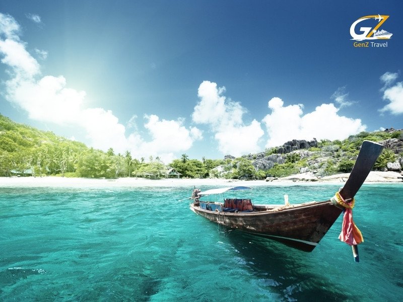 Traditional longtail boat sailing through crystal clear waters between tropical islands in Thailand