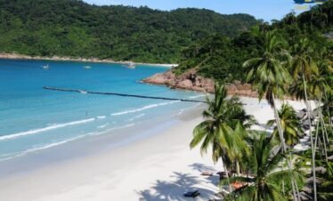 Beachfront luxury resort in Pattaya with calm ocean waves and tropical palm trees at sunset