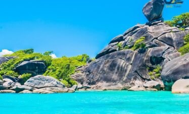 Crystal clear water at Similan Islands with snorkelling tourists and vibrant coral reef scenery