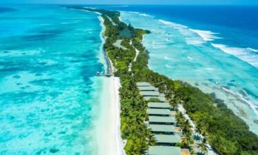 Aerial view of Canareef Resort Maldives with overwater villas, turquoise lagoons, and lush tropical greenery.