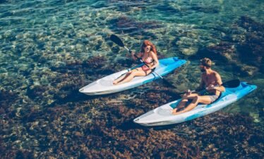 Guests enjoying water sports and spa facilities at Canareef Resort Maldives surrounded by turquoise waters.