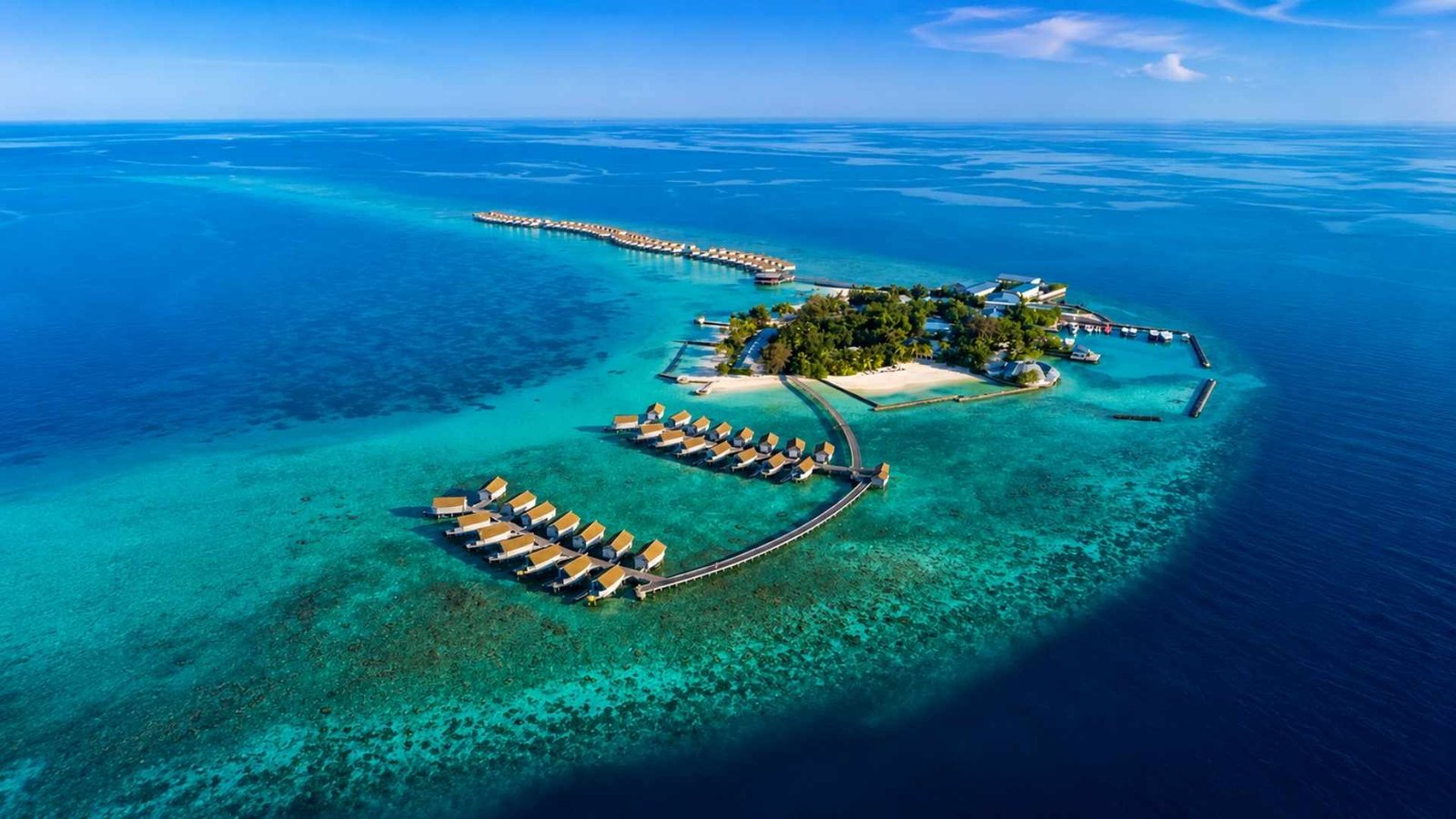 Aerial view of Centara Ras Fushi Resort Maldives with turquoise lagoon, overwater villas, and tropical island scenery.