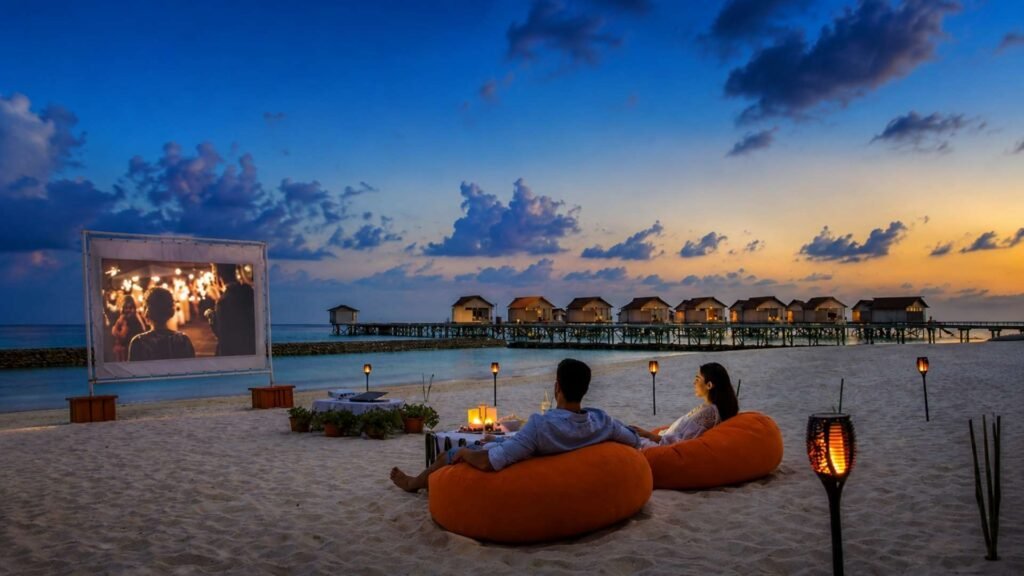 Couples relaxing on bean bags during a romantic beach movie night at a Maldives adults-only resort.