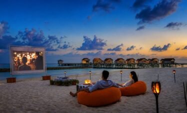 Couples relaxing on bean bags during a romantic beach movie night at a Maldives adults-only resort.