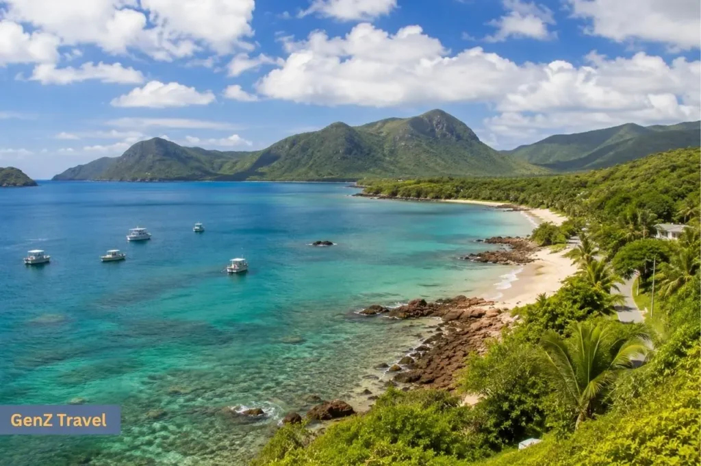 Secluded turquoise bay with white-sand beach, fishing boats and forested mountains in the Con Dao Islands