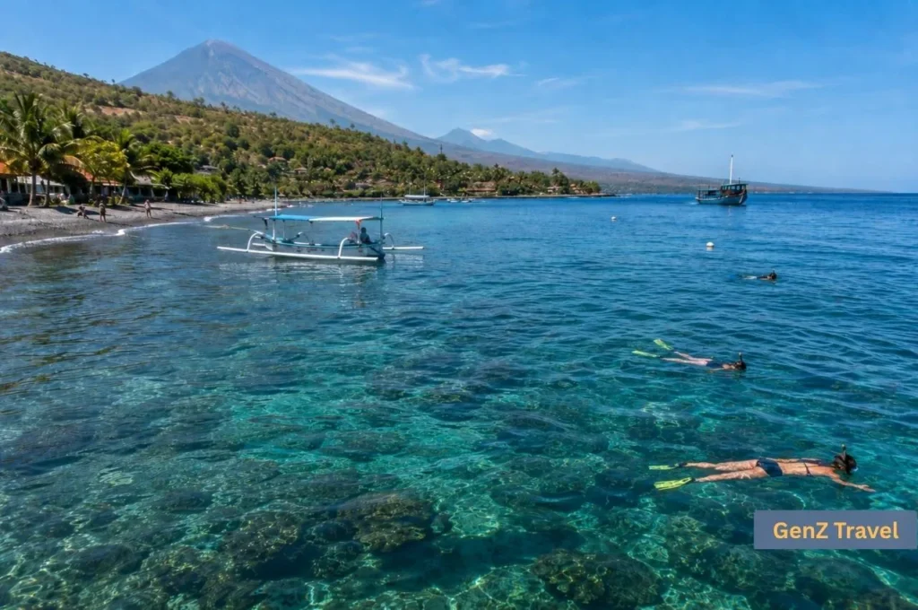 Snorkellers exploring clear coastal waters in Amed with Mount Agung in the background.