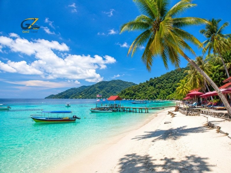 Tropical beach in Malaysia with turquoise water, white sand, palm trees and traditional boats