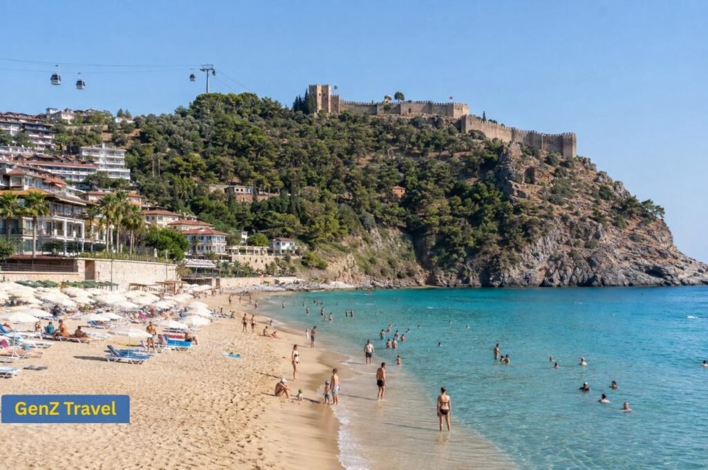 Cleopatra Beach in Alanya with sandy shore, clear water, swimmers, hilltop castle and cable cars