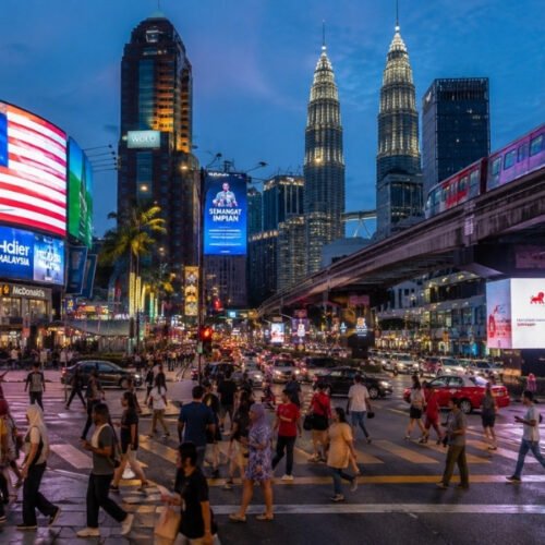 Busy Kuala Lumpur city centre at night with Petronas Twin Towers, traffic, pedestrians and illuminated streets