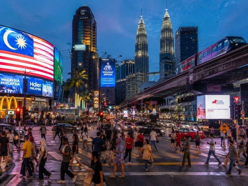 Busy Kuala Lumpur city centre at night with Petronas Twin Towers, traffic, pedestrians and illuminated streets