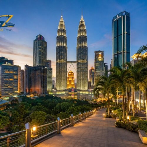 Kuala Lumpur skyline at sunset with the illuminated Petronas Twin Towers and landscaped city surroundings