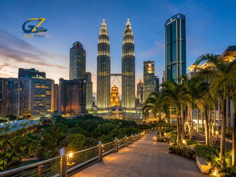 Kuala Lumpur skyline at sunset with the illuminated Petronas Twin Towers and landscaped city surroundings