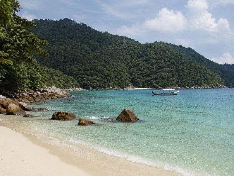 Langkawi beach with white sand, turquoise water, palm trees and limestone islands