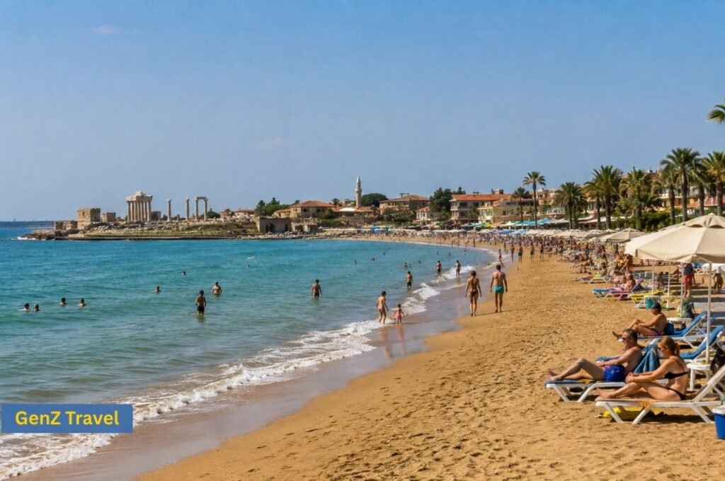 Side West Beach with sandy shoreline, resort sun loungers and ancient ruins visible beside the old town
