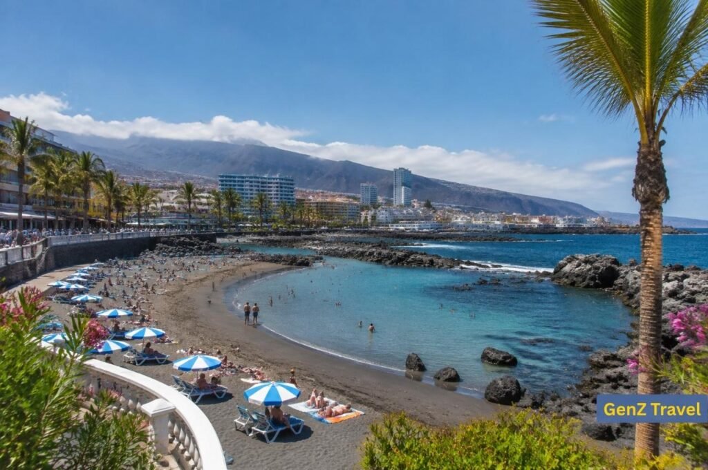 Tenerife beach with black sand, palm trees, clear sea and mountain resorts in the Canary Islands