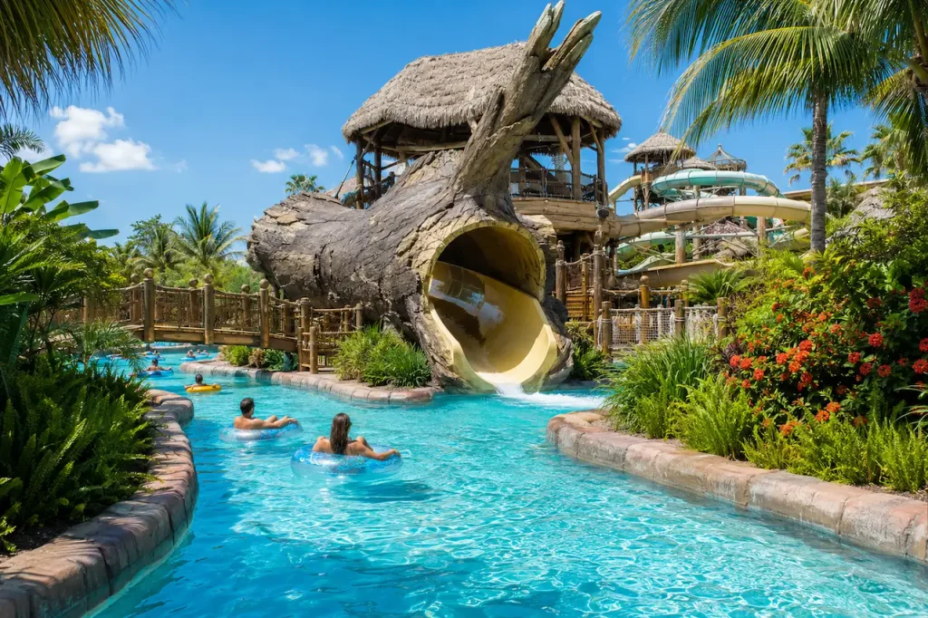 Visitors floating along a tropical lazy river beside water slides at an Antalya water park.