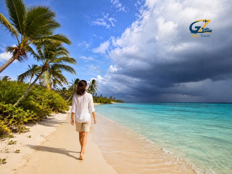 Woman walking along a Caribbean beach beneath storm clouds, illustrating when is hurricane season in the Caribbean.