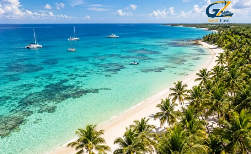 Aerial view of a Caribbean tropical coastline with turquoise waters, white-sand beaches, palm trees and luxury yachts.