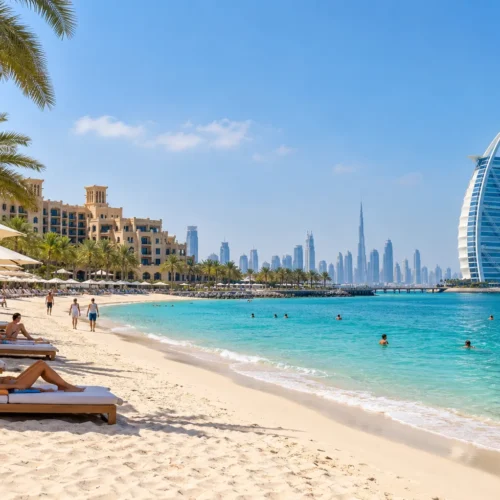 Sunny Dubai beach with turquoise water, palm trees, sun loungers and the Burj Al Arab overlooking the coastline