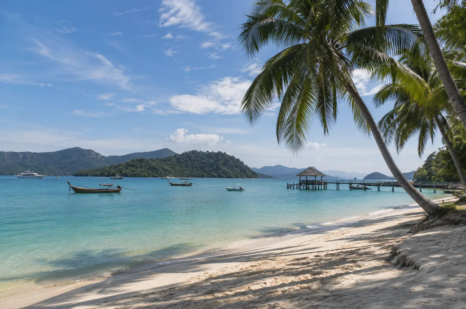 Peaceful tropical beach in Malaysia with white sand, turquoise waters, palm trees, traditional boats and lush green islands.
